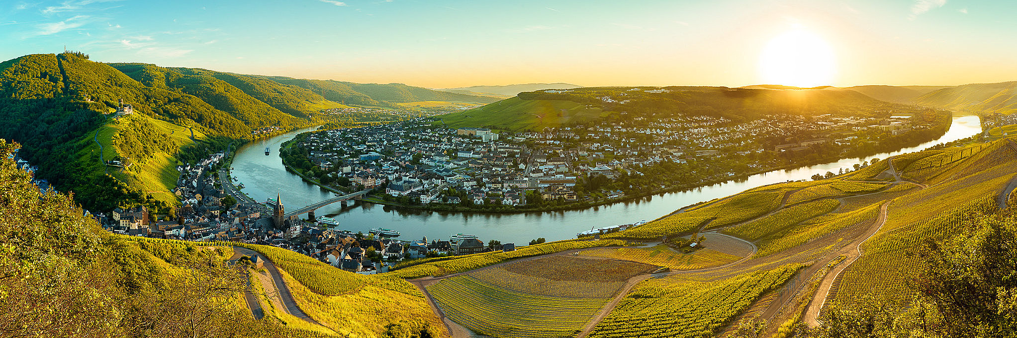 Moselpanorama mit Blick auf Bernkastel-Kues Moselpanorma mit Blick auf die Weinberge, die Mosel und die Stadt in Bernkastel-Kues im Abendlicht.