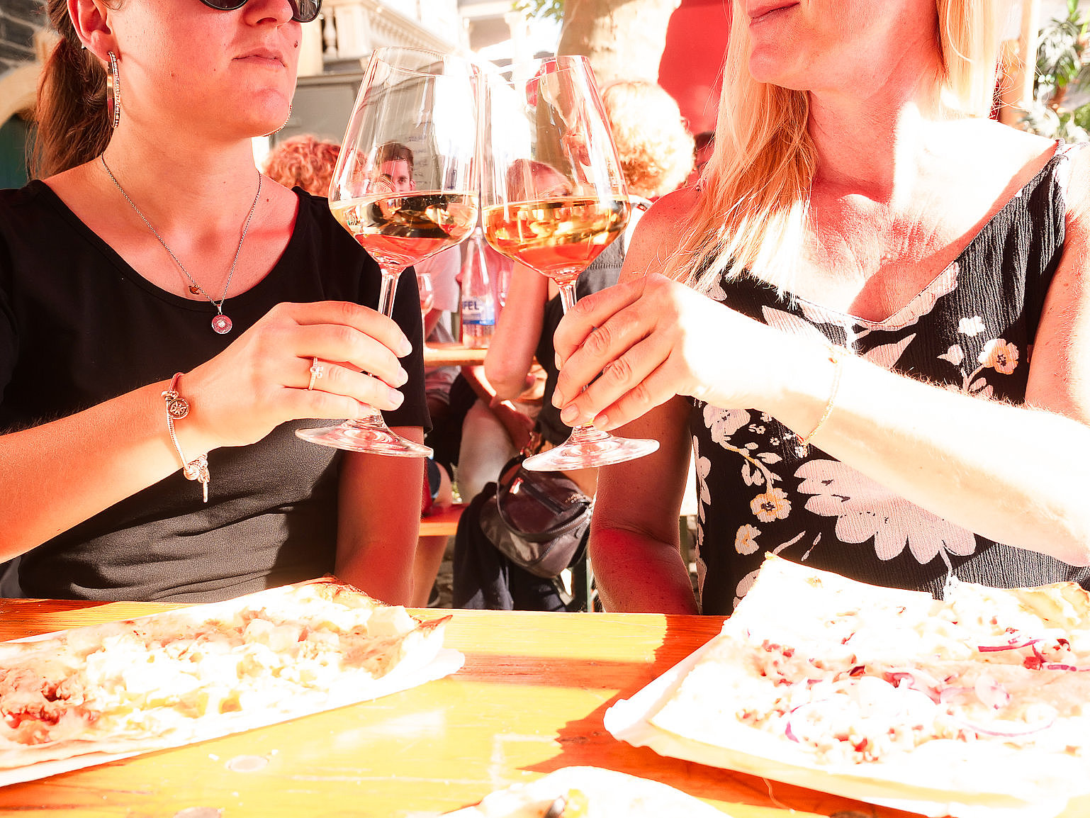 Weinfest und Genuss Das Bild zeigt zwei Personen, die an einem Tisch sitzen. Sie besuchen das Weinfest der Mittelmosel und genießen ein Glas Wein und essen Flammkuchen.