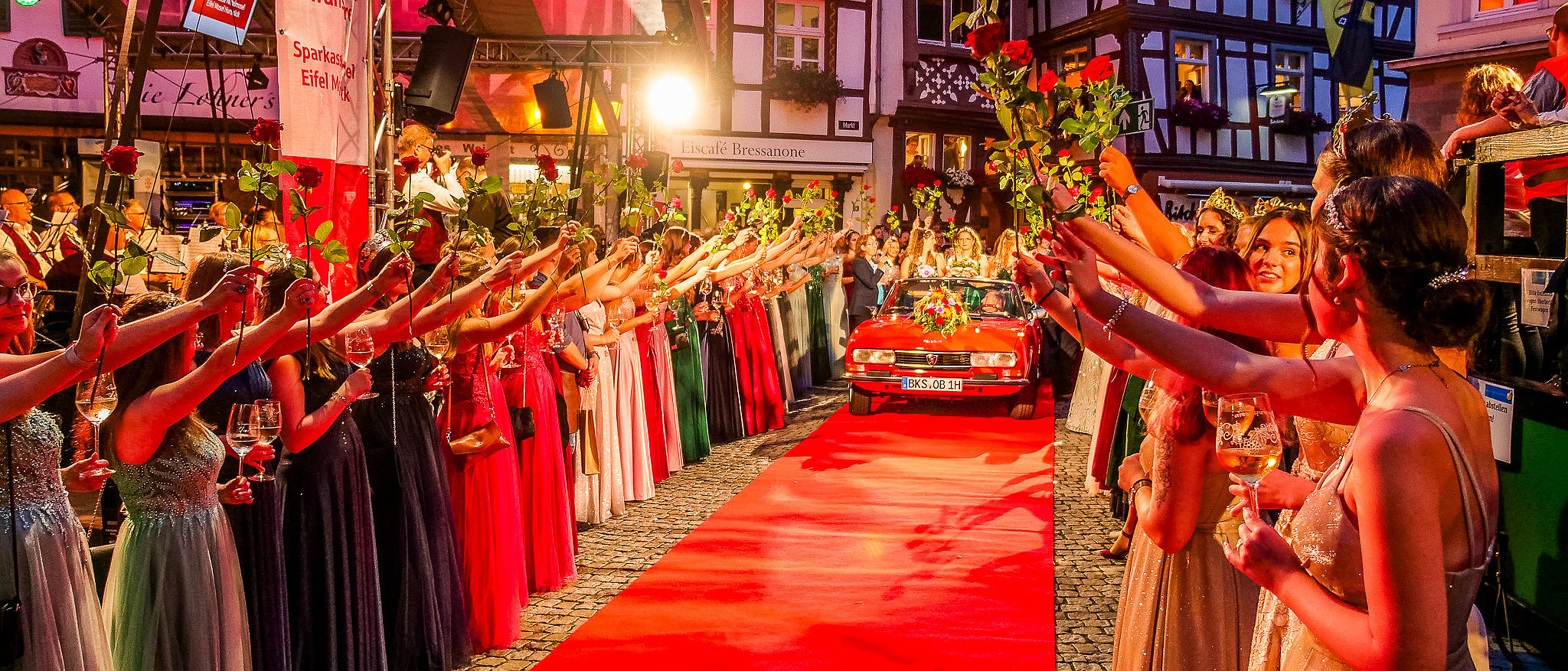 Empfang der Mosella auf dem roten Teppich des Weinfestes der Mittelmosel in Bernkastel-Kues Das Foto zeigt die Mosella mit ihren zwei Weinprinzessinnen, die in einem roten Cabriolet auf den roten Teppich des Weinfestes der Mittelmosel auf den Marktplatz in Bernkastel-Kues gefahren werden. Viele weitere Weinhoheiten stehen mit hochgehaltenen Rosen Spalier.